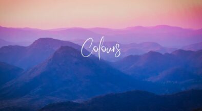 Text: Colours on a background silhouette of mountains against clouds